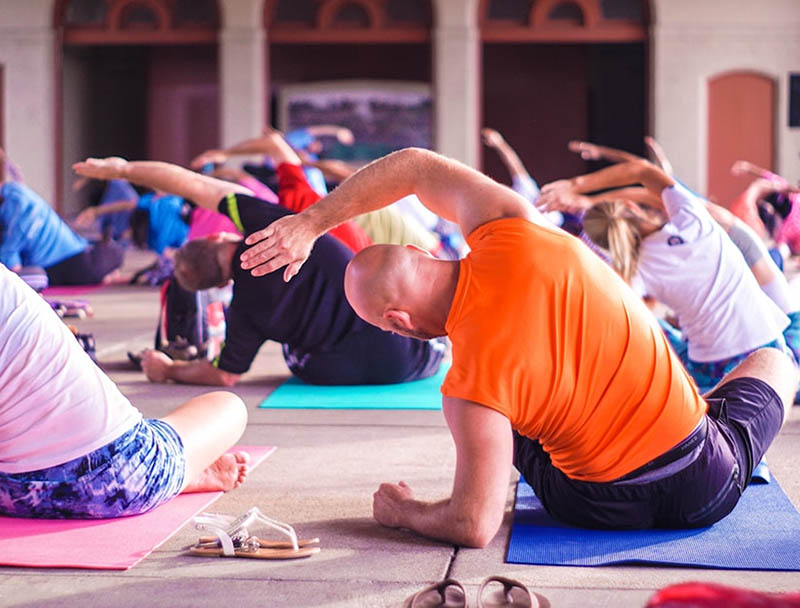Un groupe de personnes pratique le yoga en extérieur, en pleine séance d’étirements synchronisés sur des tapis colorés. Un groupe de personnes pratique le yoga en extérieur, en pleine séance d’étirements synchronisés sur des tapis colorés.