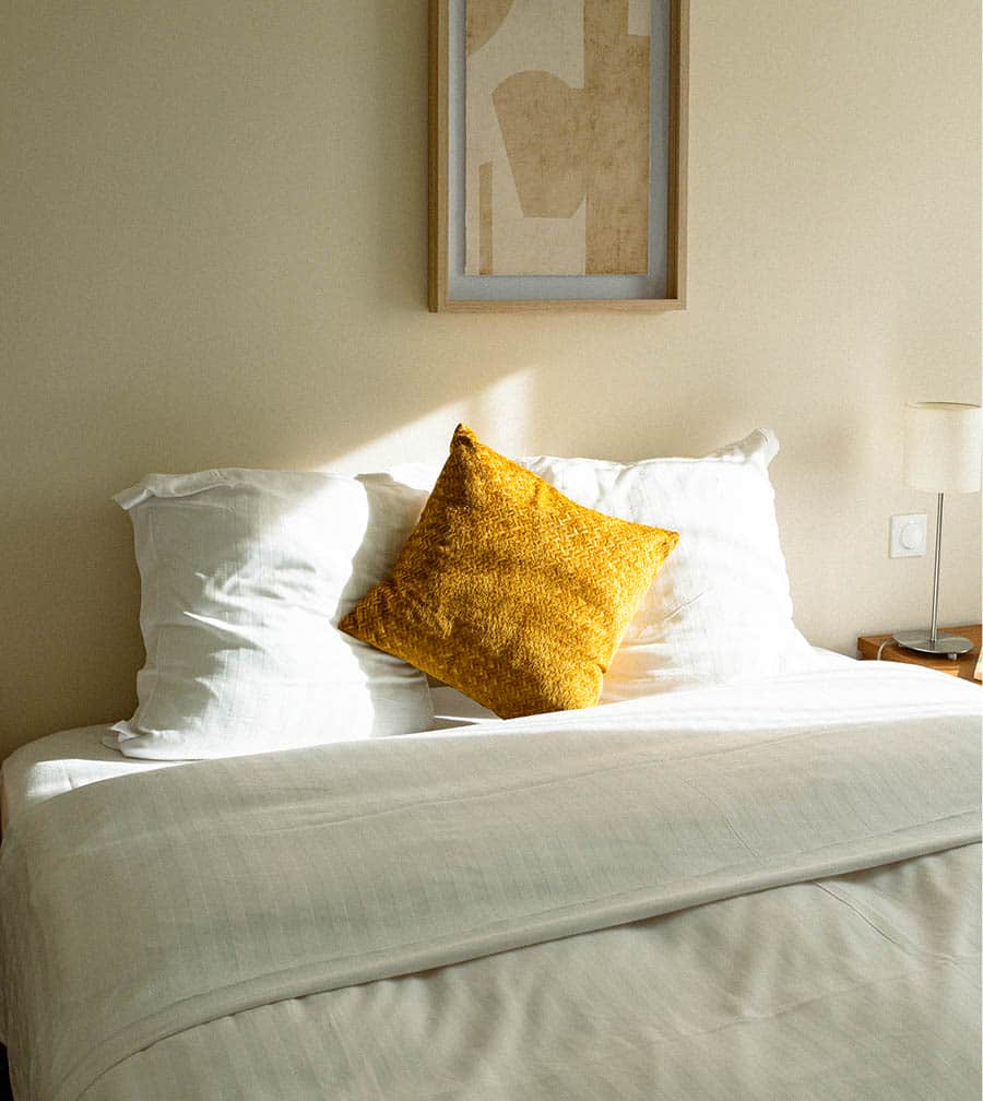 Chambre apaisante avec linge blanc impeccable et coussin ocre, promesse de nuits sereines. Chambre apaisante avec linge blanc impeccable et coussin ocre, promesse de nuits sereines.
