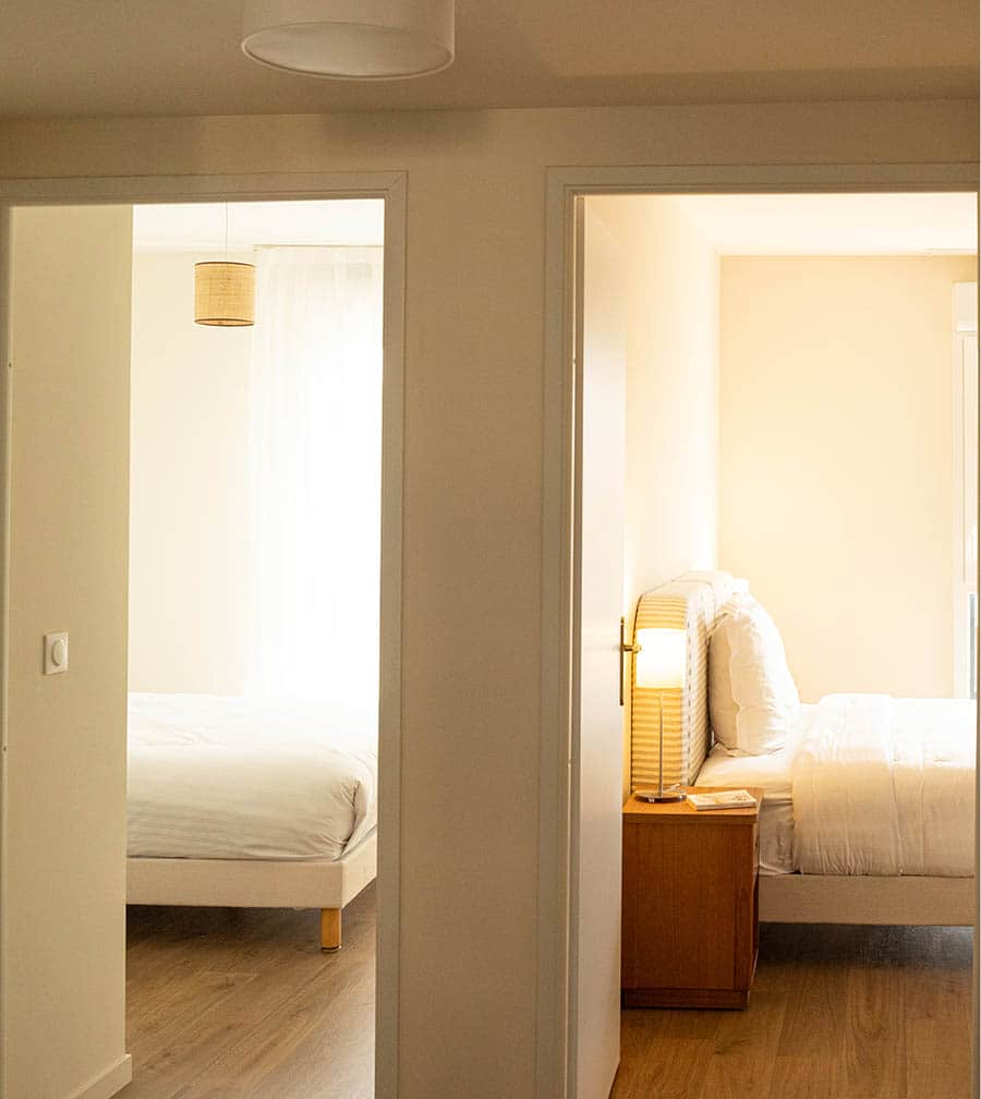 Chambre douce et raffinée avec tête de lit rayée, linge blanc immaculé et chevets chaleureux. Chambre douce et raffinée avec tête de lit rayée, linge blanc immaculé et chevets chaleureux.