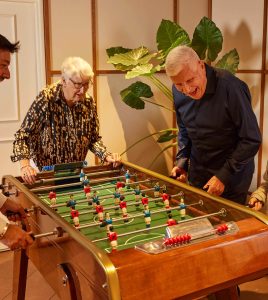 Casa Barbara Nice : deux membres du club hôtel jouent ensemble au baby-foot dans la salle de jeux chaleureuse de notre résidence hôtel-club.