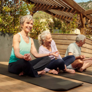 Elderly people smiling while doing yoga.